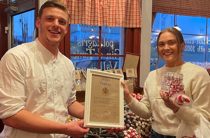 A pair of candy makers holding a diploma