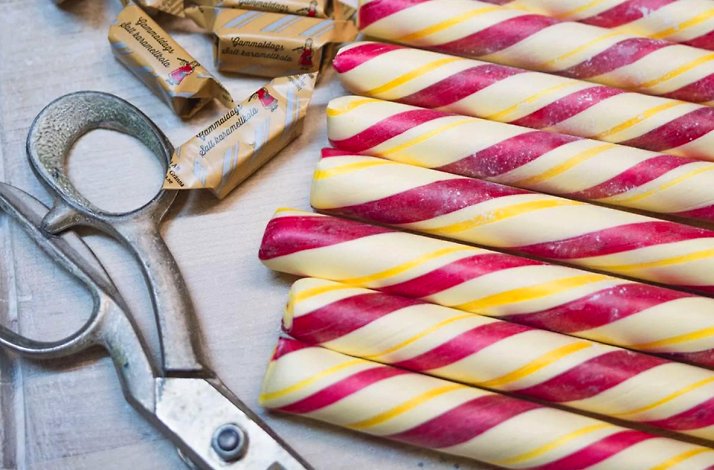 Polkapojkarna candy sticks, a type of Swedish confectionery known as polkagris next to a scissor 