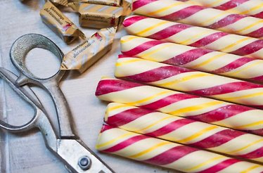 Polkapojkarna candy sticks, a type of Swedish confectionery known as polkagris next to a scissor 