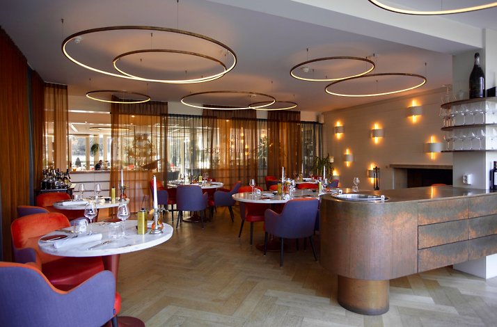 Modern restaurant with round tables and stylish lighting.