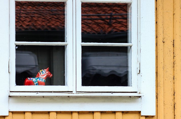 Outside view of a red Dala horse on a white windowsill.