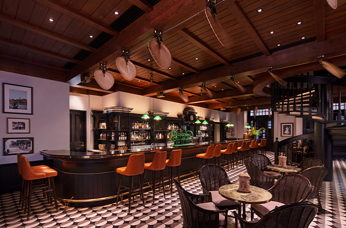 Hotel bar with wooden ceiling, leather stools, and patterned tile floor