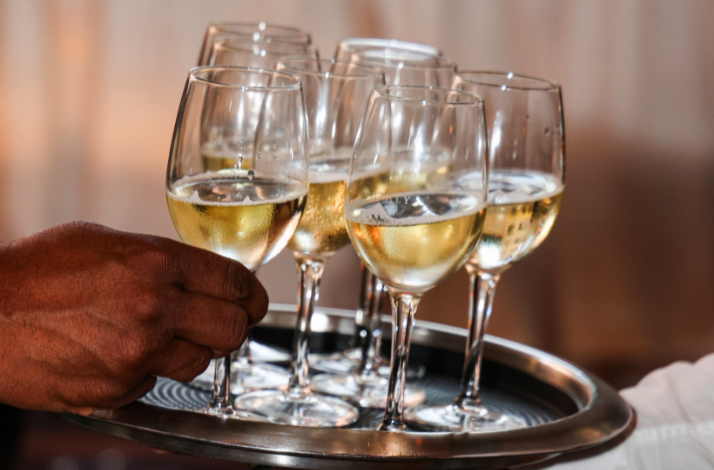 A tray with multiple glasses of white wine being served.