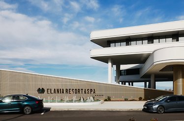Entrance of Elania Resort & Spa with parked cars and fountains.
