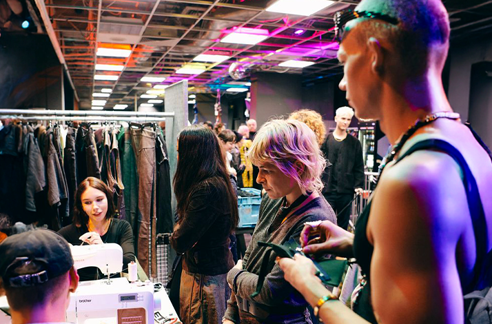 A busy fashion event with people gathering around a sewing station at PLATTE Berlin.