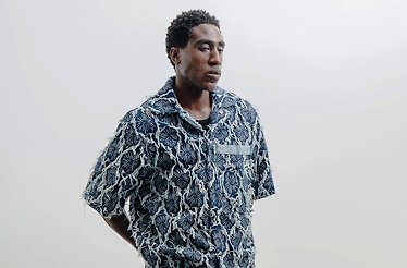 A model wearing the Nowrubi Raffia Denim Shirt in Indigo Blue.
