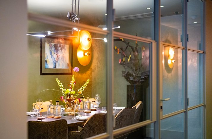 An elegant large table at Senses Restaurant seen through a windowed door.