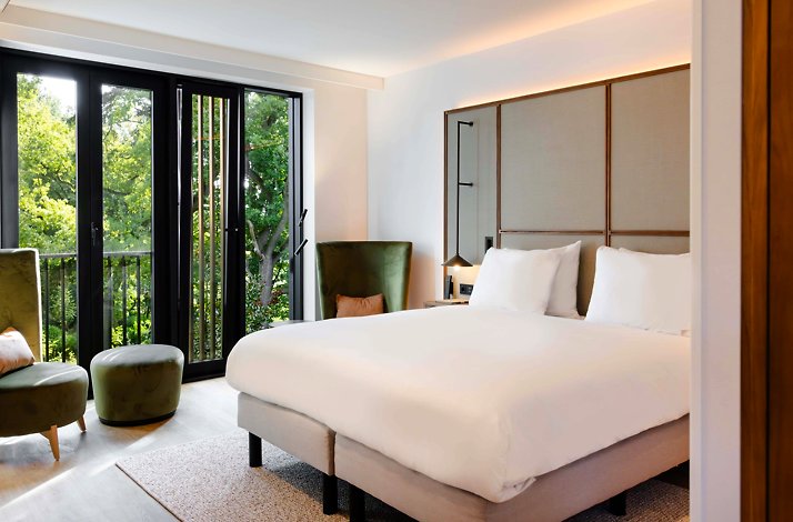 An elegantly arranged room with a large bed and a balcony at Kasteel Steenenburg.