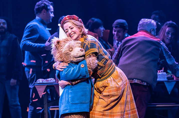Paddington Bear shares a warm hug with a family member in a joyful musical scene
