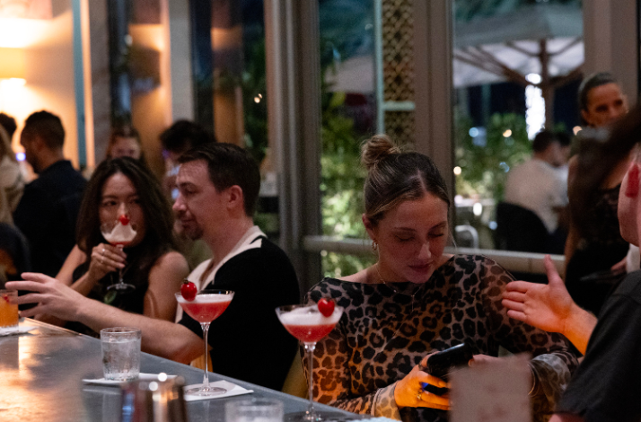 People sitting at a bar with cocktails.