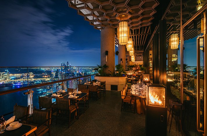 An open-air terrace of Mott 32 Dubai restaurant overlooking nighttime Dubai.