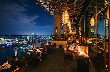 An open-air terrace of Mott 32 Dubai restaurant overlooking nighttime Dubai.