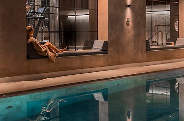 A person sitting next to a swimming pool at the  The Edwardian Hotel Manchester spa.