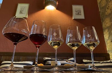 Display of five wine glasses filled with red and white wine on a table.