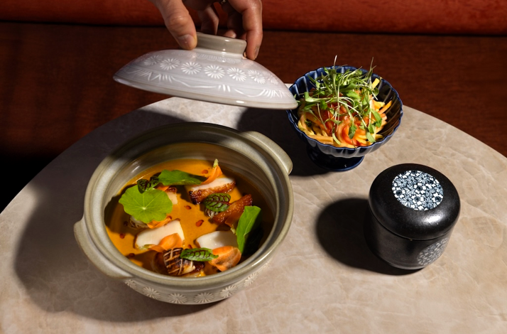 Chef-crafted course revealed in immersive art dining setting.
