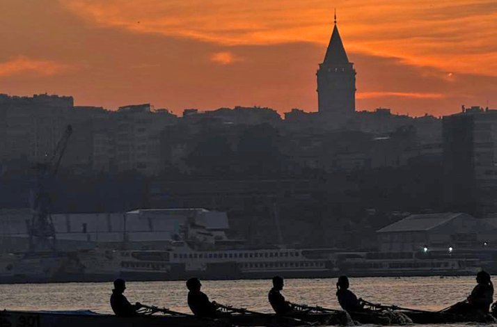 Two rowers on calm water during a golden sunrise.