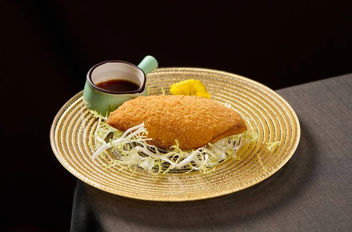 A crispy, golden-fried bean curd sheet shrimp cake served on a glass plate with dipping sauce.