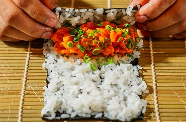 Fresh sushi being hand‑rolled, reflecting the finely crafted dishes featured in the Goldfish Bites experience.
