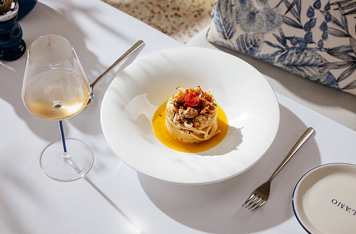 Gourmet pasta dish served with a glass of white wine.