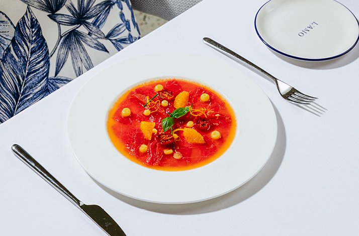 Vibrant seafood dish with citrus and garnishes on a white plate.
