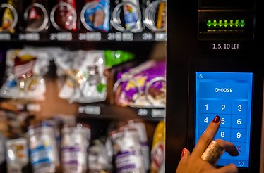 A person using a modern, cashless smart O' Fresh vending machine.