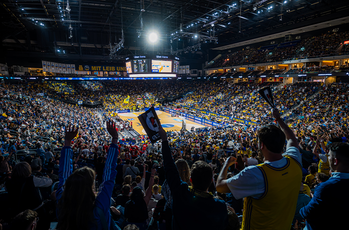 View of the basketball court from crowded, cheering stands.