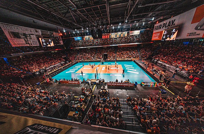 BR Volleys hosting FT 1844 Freiburg at a packed Max-Schmeling-Halle, with players competing on a teal and orange volleyball court.