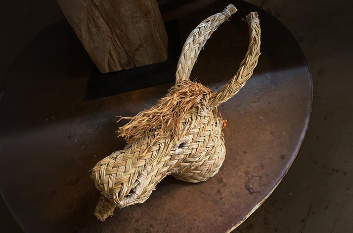 A handwoven eco-trophy in the shape of a bull’s head, crafted from natural esparto fibers, displayed on a dark wooden surface.