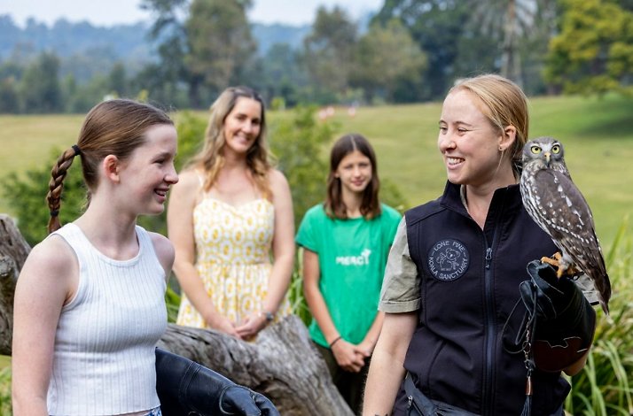 Wildlife keeper presenting an owl to guests during a sanctuary tour.