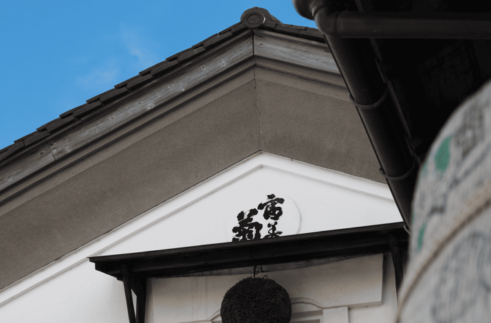 Exterior view of Fumigiku Shuzo brewery with a traditional Japanese design and a sake cedar ball hanging above the entrance.