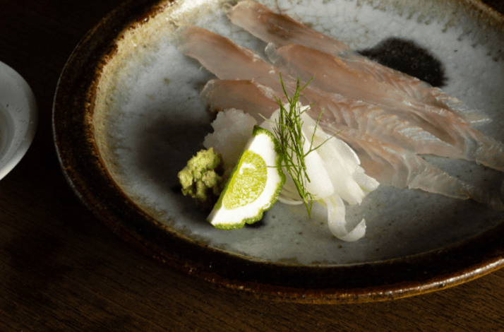 Delicately sliced, translucent white-flesh sashimi is arranged on a plate.