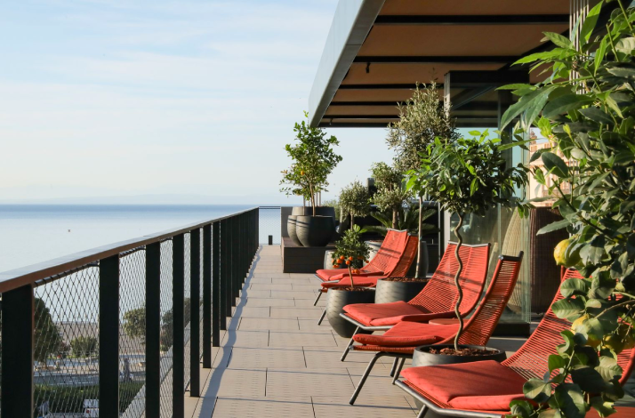 Red cozy chairs on the open terrace with a sea view at Keight Hotel Opatija.