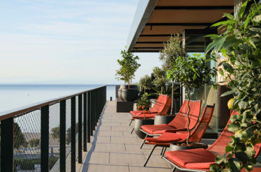 Red cozy chairs on the open terrace with a sea view at Keight Hotel Opatija.