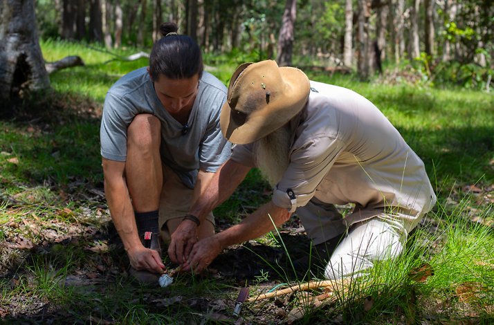 Rick J Petersen demonstrating with a participant a primitive fire-starting technique.