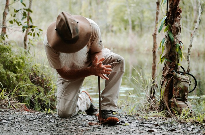 Rick J Petersen is demonstrating a primitive fire-starting technique, such as using a hand drill.