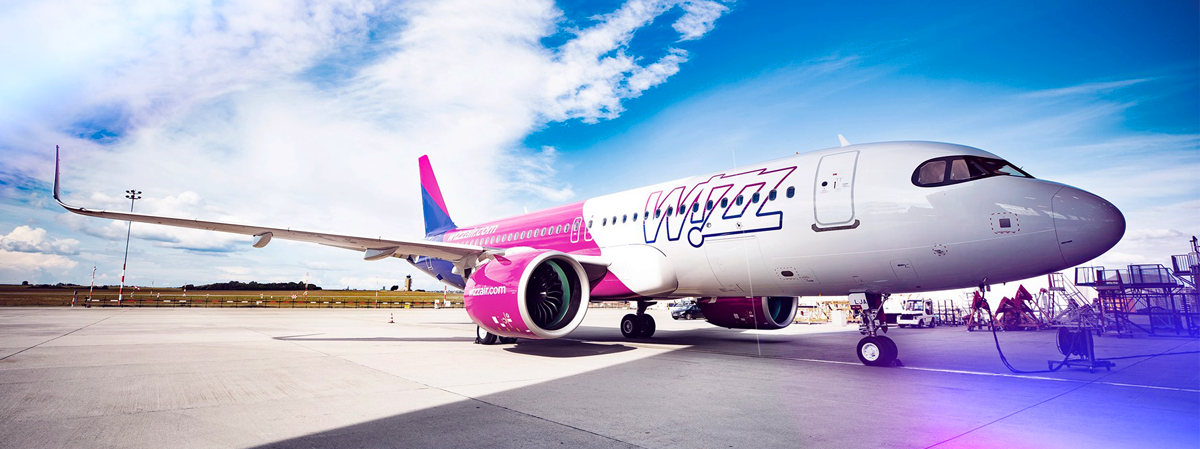 Banner image with Wizzair airplane in the airport ground field.