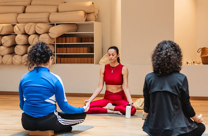Three women practicing yoga together in a serene class setting, focusing on their poses and breathing.