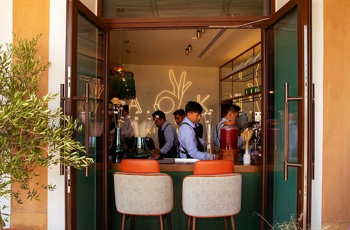 An open doorway looks into interior of A.O.K. Kitchen, where staff work behind a counter.