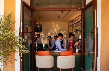 An open doorway looks into interior of A.O.K. Kitchen, where staff work behind a counter.
