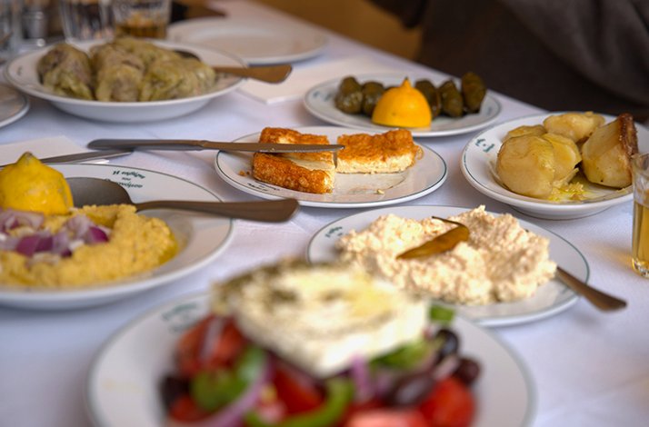 A table spread of various Greek meze dishes on white plates.
