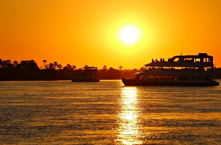 A silhouette of a boat gliding on the Nile River during a vibrant sunset, with warm colors reflecting on the water.
