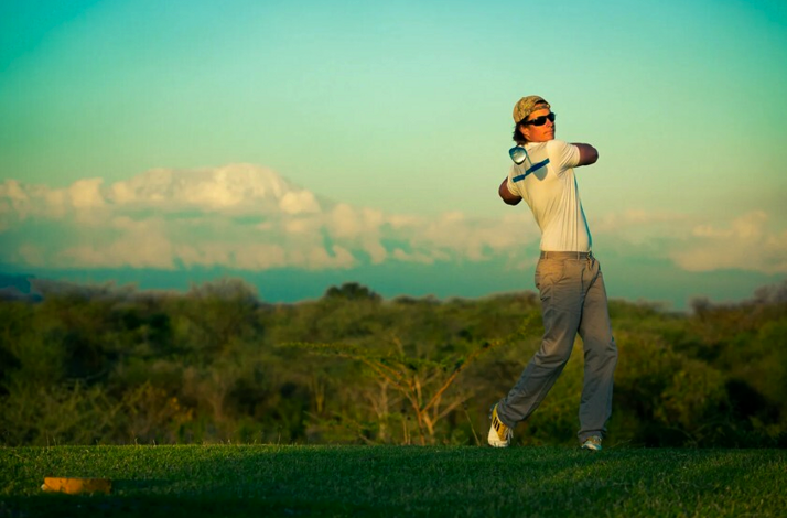 Golfer swinging on a fairway with views of Mount Kilimanjaro.