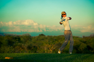 Golfer swinging on a fairway with views of Mount Kilimanjaro.
