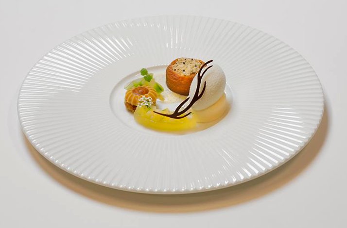 An elegantly plated fine dining dessert is presented with precision, showcasing delicate textures and refined techniques in a calm, minimalist setting that highlights craftsmanship and attention to detail.