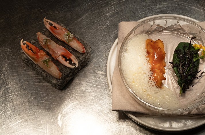 Fresh seafood and carefully composed elements plated in a working kitchen environment, capturing the focused intensity and craftsmanship behind a high-level culinary performance.