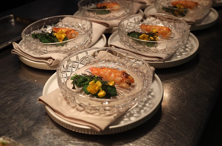 Beautifully plated seafood dishes prepared in sequence on a stainless steel counter, conveying the energy, precision, and teamwork of a professional kitchen in motion.