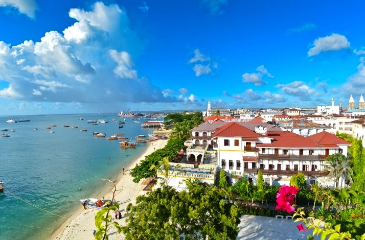  A scenic view of a beach with city buildings in the background under a clear blue sky.