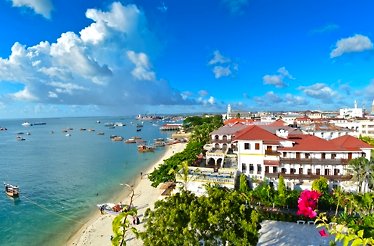  A scenic view of a beach with city buildings in the background under a clear blue sky.