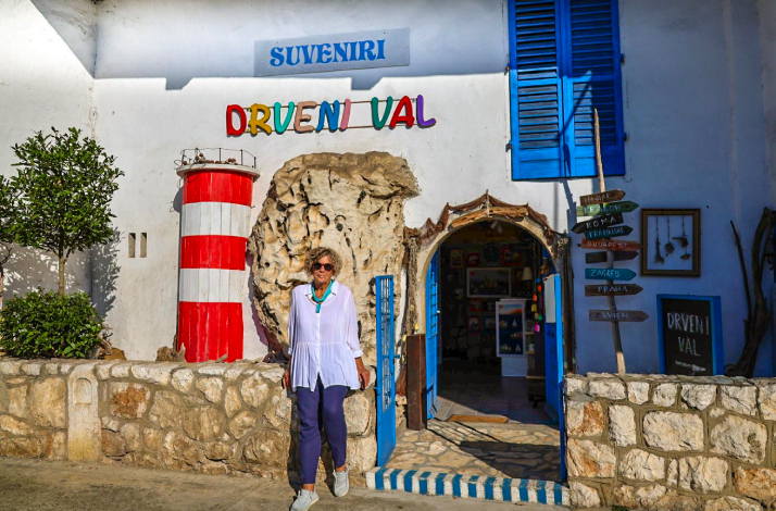 Entrance to Drveni Val souvenir shop with a lighthouse decoration and vibrant signage.