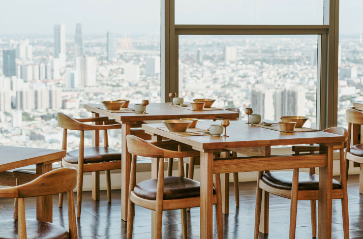 Dining tables set with bowls and cups, city view in the background.